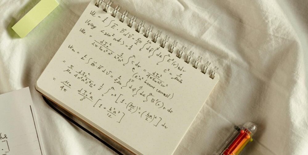 Des équations mathématiques écrites sur un cahier de notes avec un stylo sur le côté