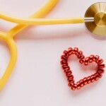 Un stéthoscope jaune et un élastique rouge en forme de coeur.