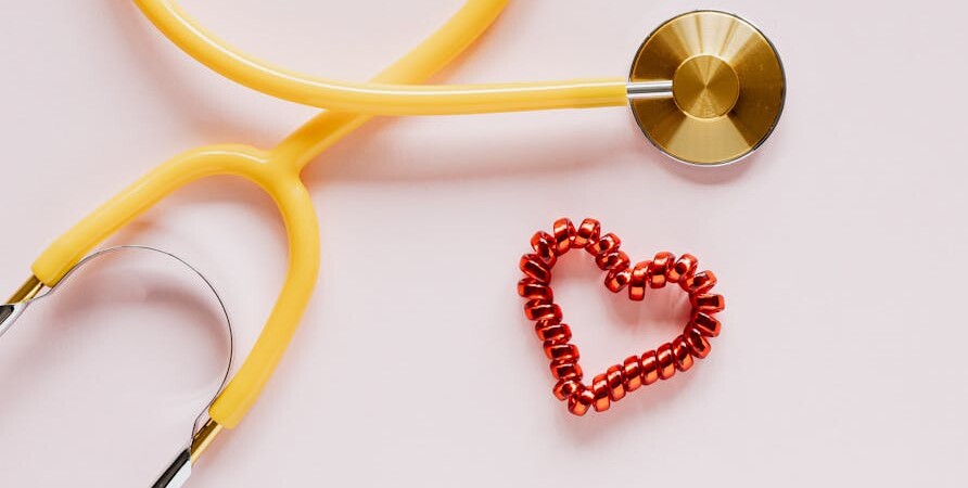 Un stéthoscope jaune et un élastique rouge en forme de coeur.